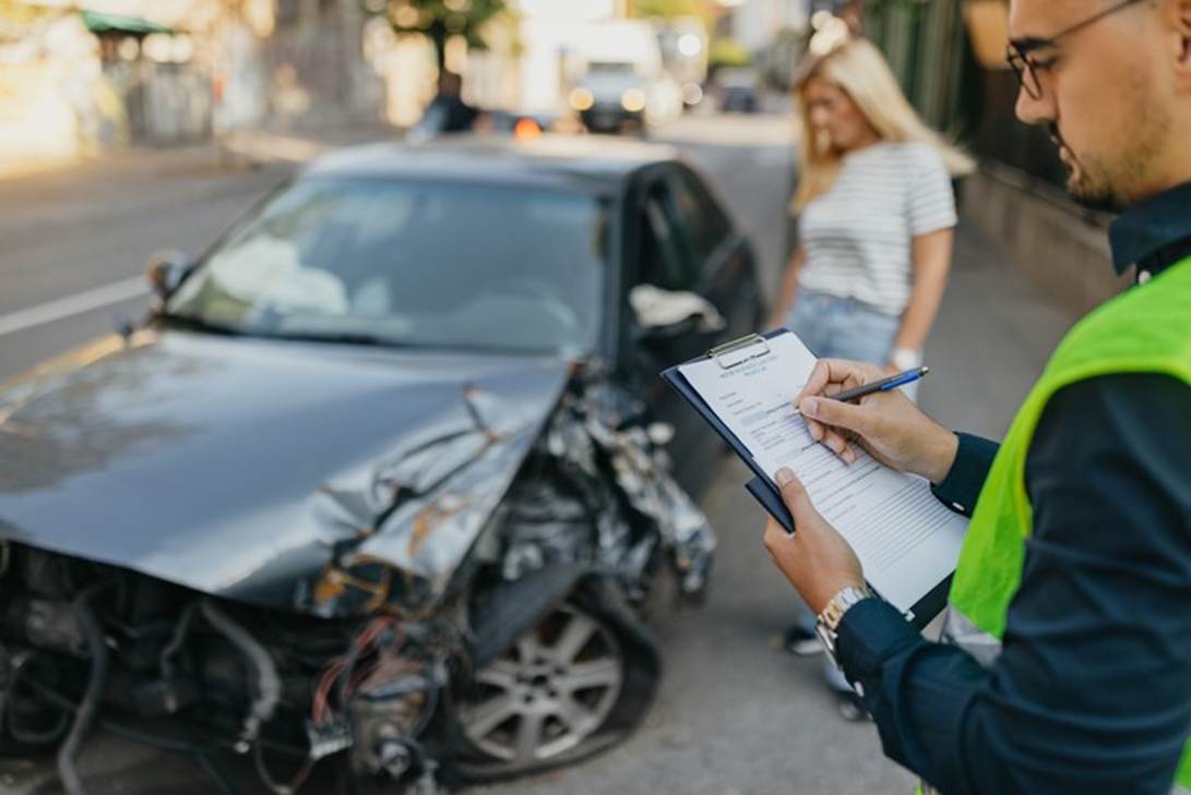 A person writing on a clipboard next to a wrecked car

AI-generated content may be incorrect.